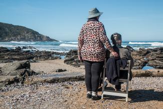 Woman standing with a seated woman, facing the ocean